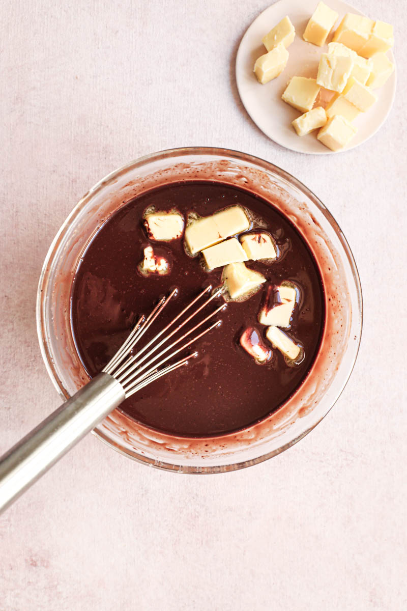 Chocolate ganache in the making: the emulsified chocolate and cream plus a part of butter with a whisk on the side.