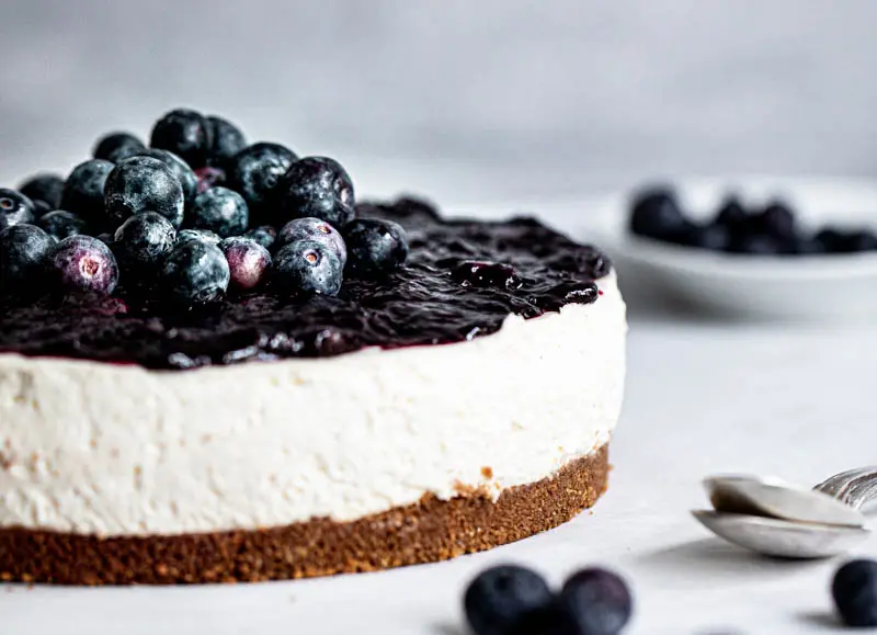 Closeup of the sliced no bake blueberry cheesecake with blueberry topping as seen from the side.