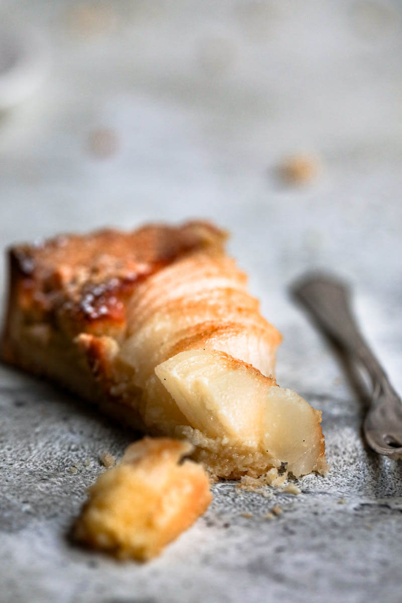 Closeup shot of one slice of the pear frangipane tart with a fork at the side