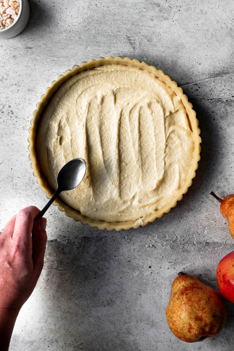 Overhead shot of one had evenly spreading the frangipane cream