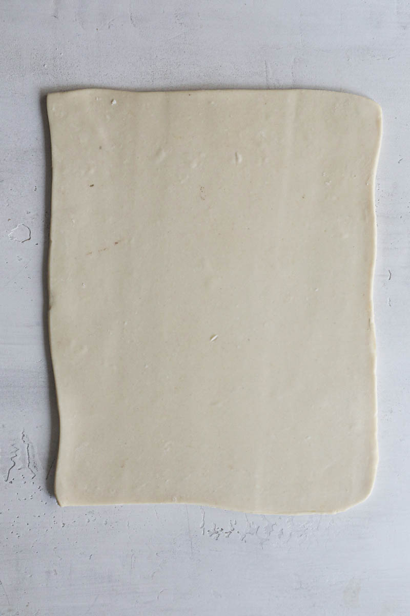 The rolled-out puff pastry dough over a white backdrop.