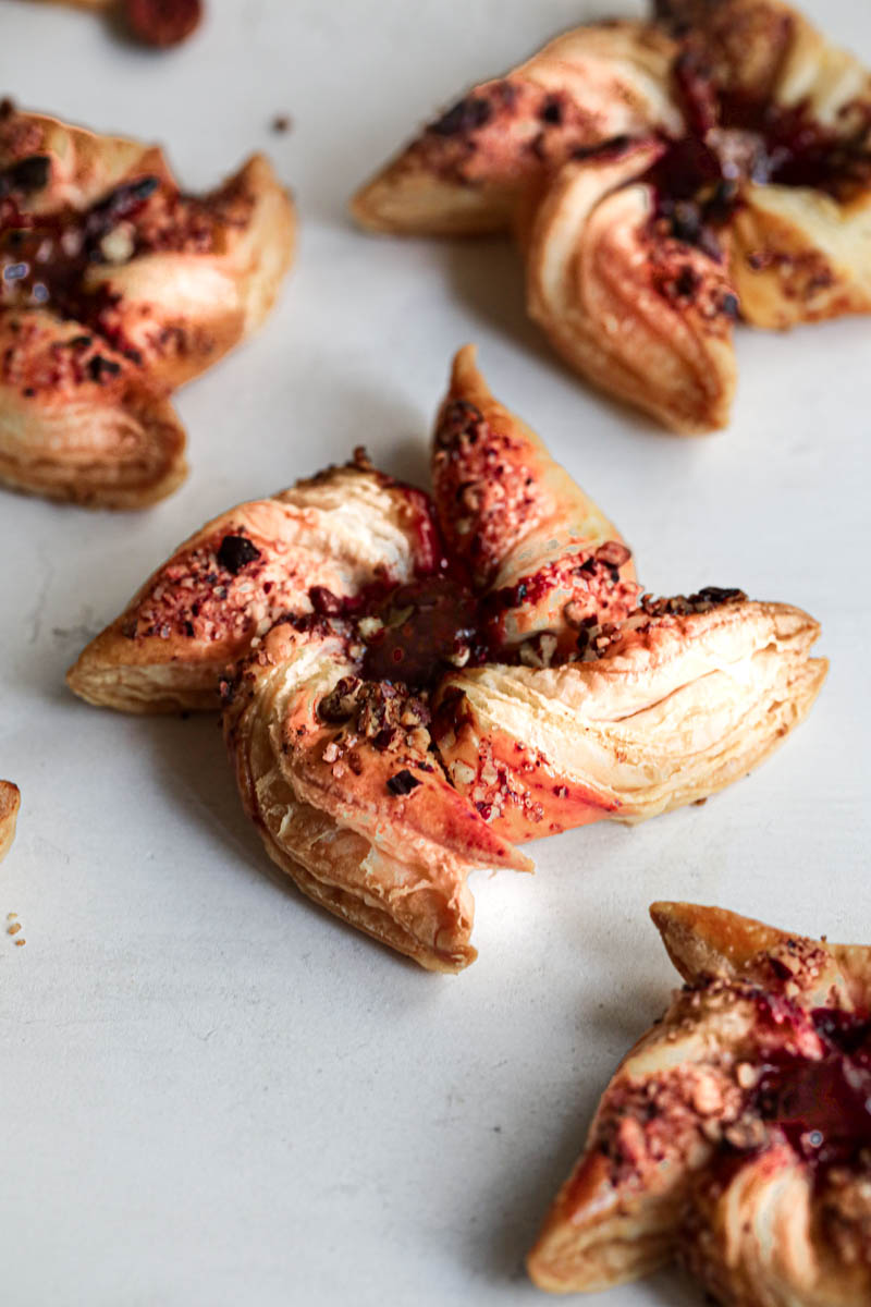 Many one raspberry pecan puff pastry pinwheels as seen from the side.