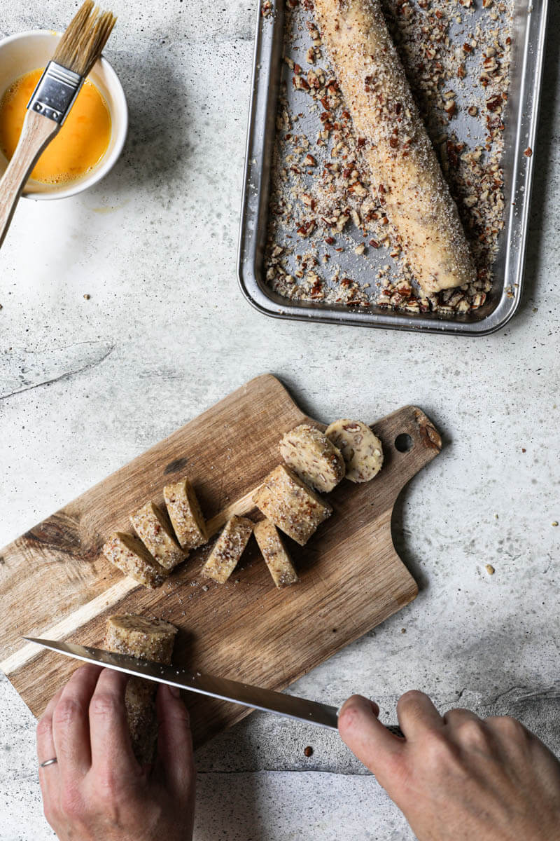 2 hands slicing the cookies using a knife