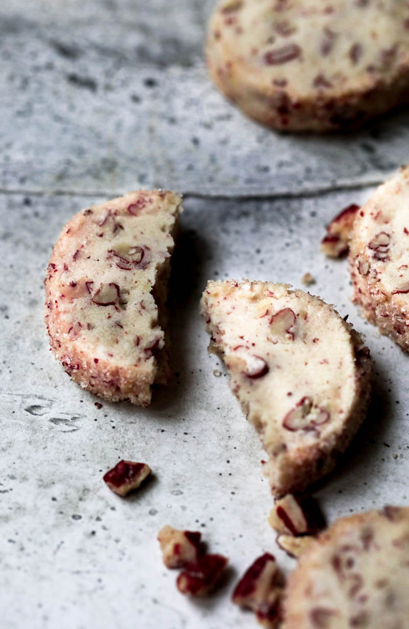 One pecan shortbread cookie broken in half surrounded by other cookies