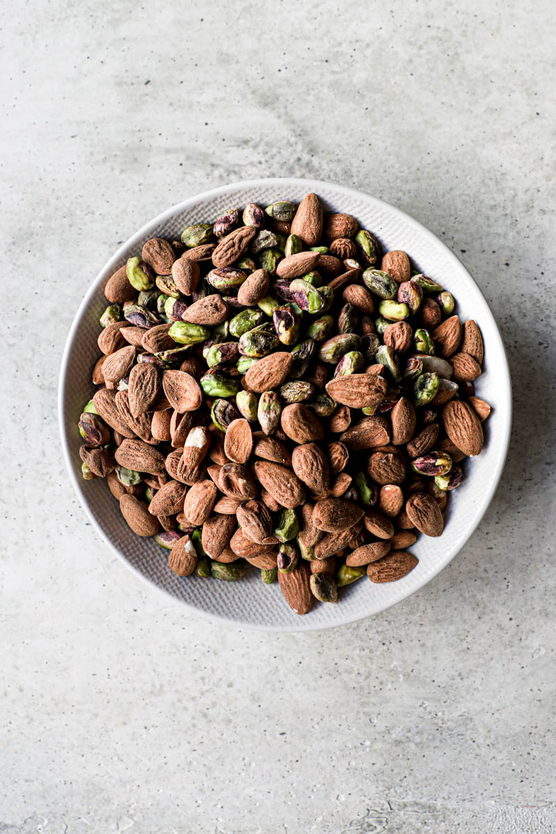 A plate full of almonds and pistachios.