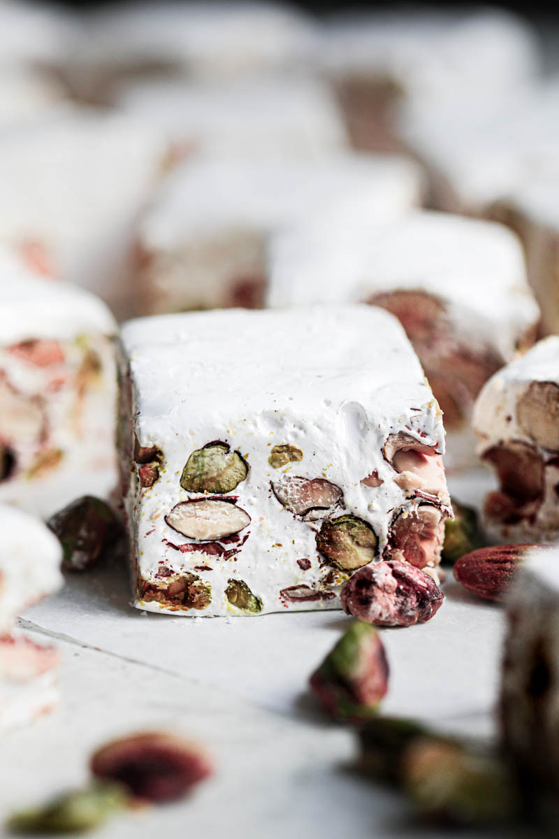 Closeup of one pistachio almond nougat bar with others blurry in the back.