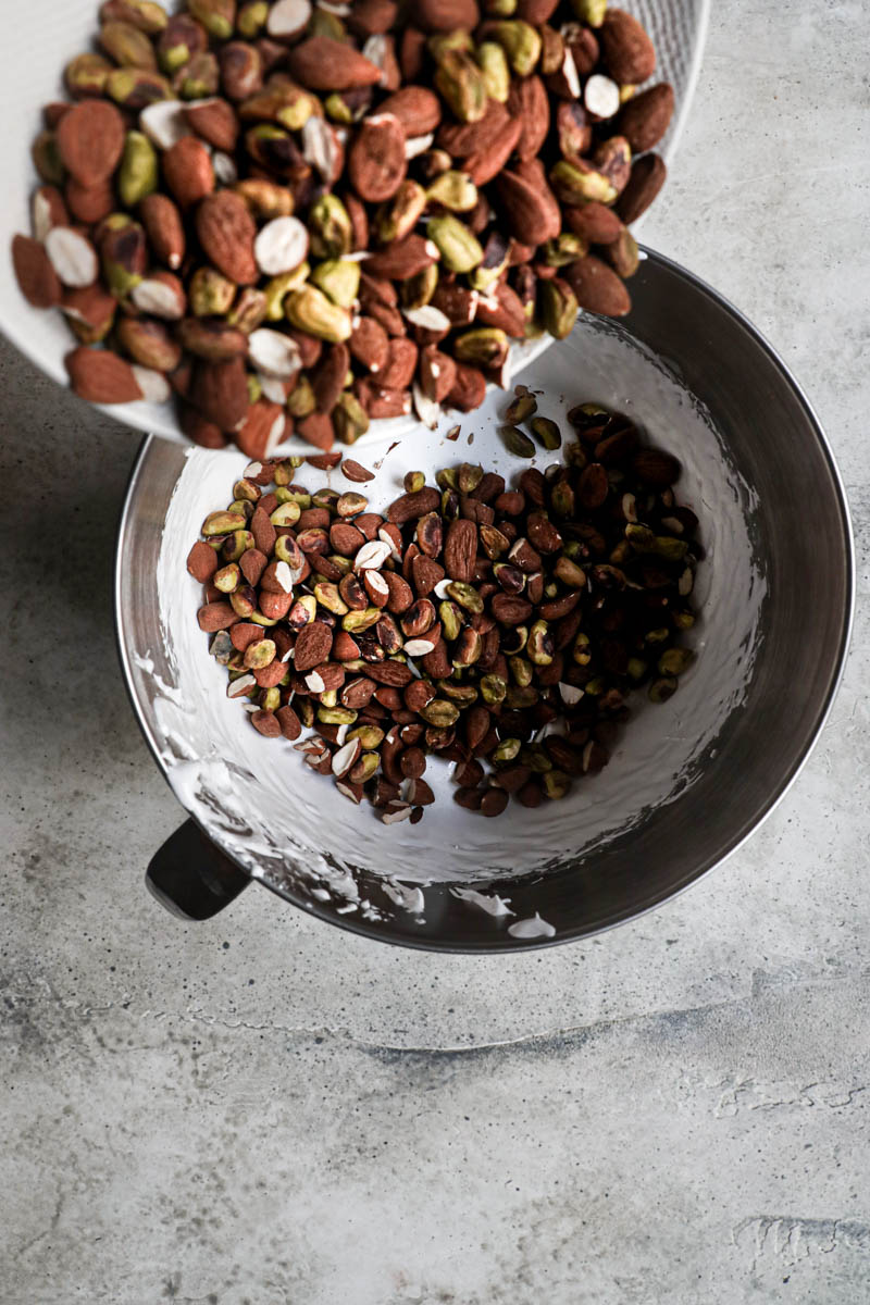 The almonds and pistachios being poured into the nougat.