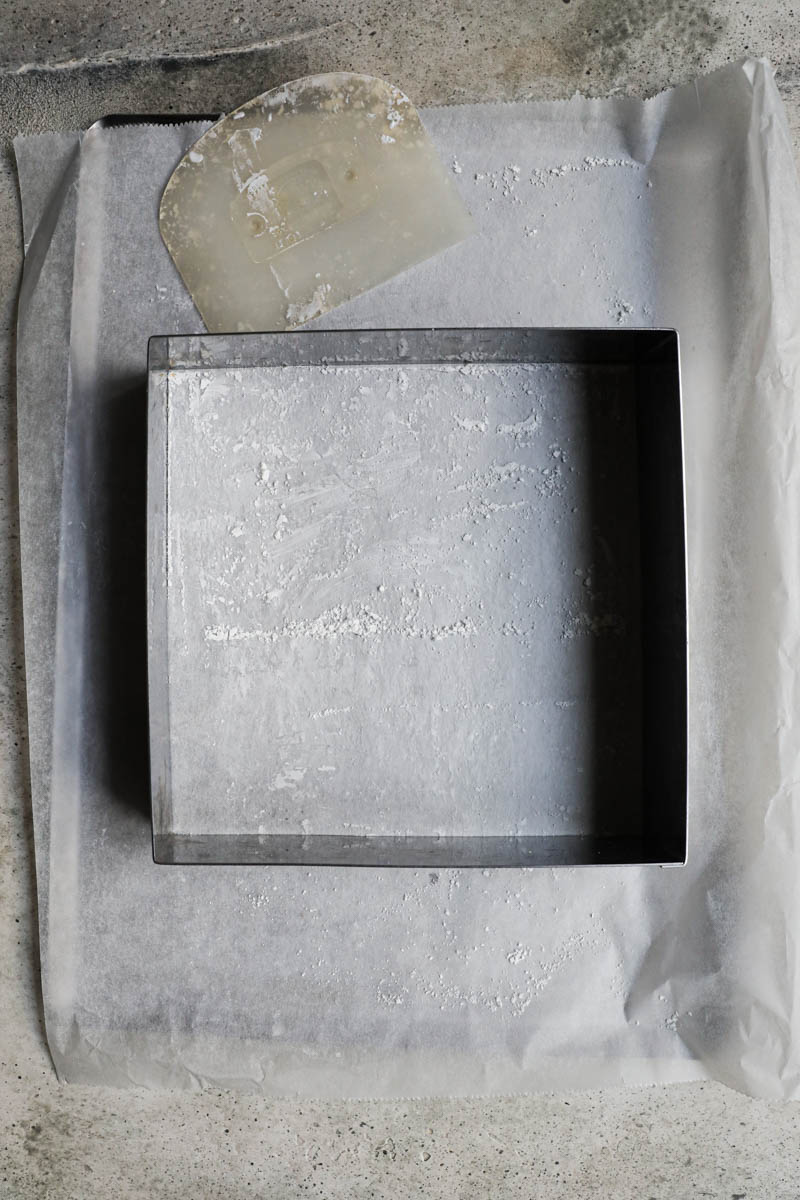 A square cake ring placed on a baking tray lined with parchment paper.