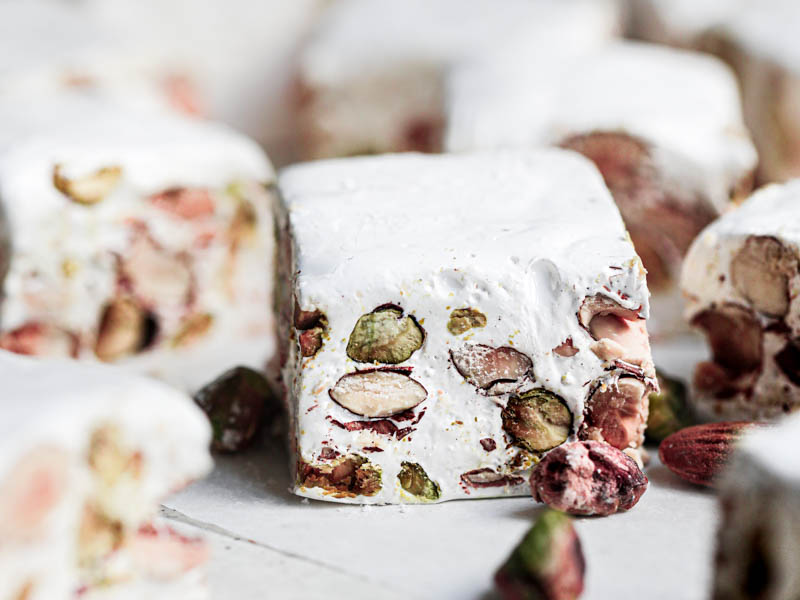 Closeup of one pistachio almond nougat bar with others blurry in the back.