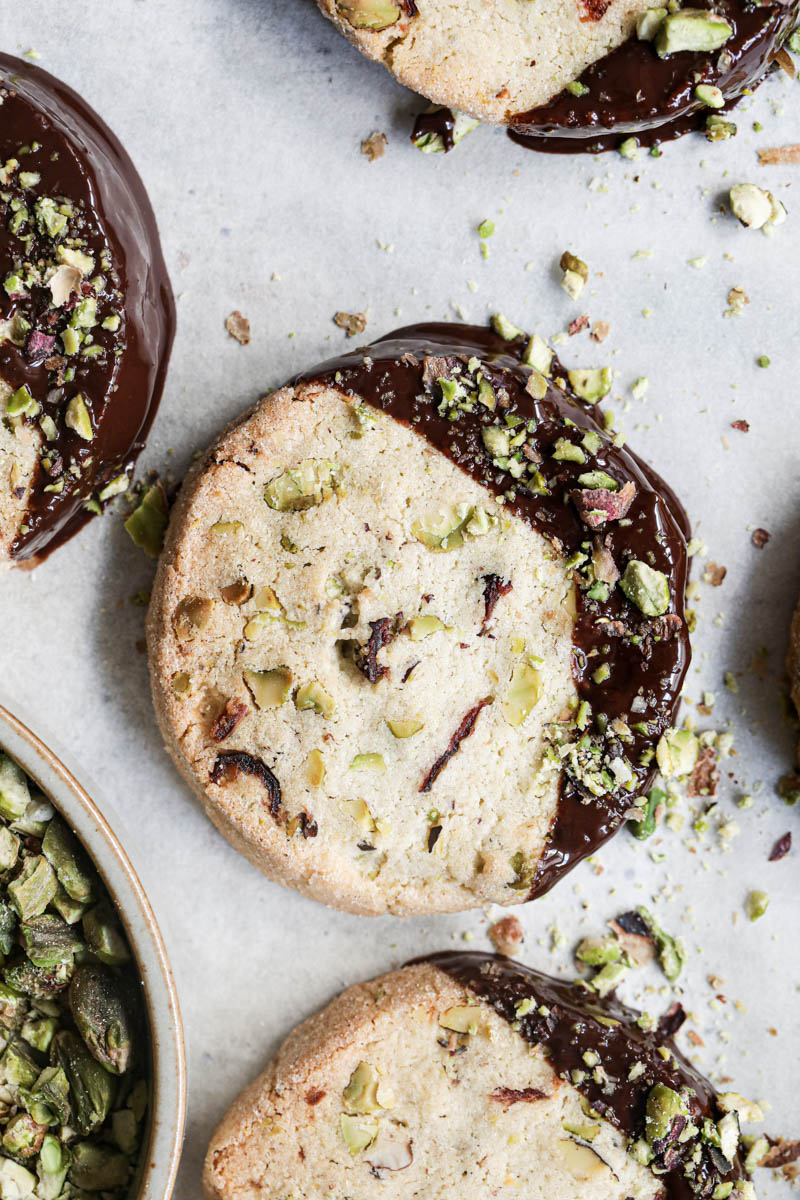Closeup of one shortbread cookie dipped in chocolate drizzled with crushed pistachios.