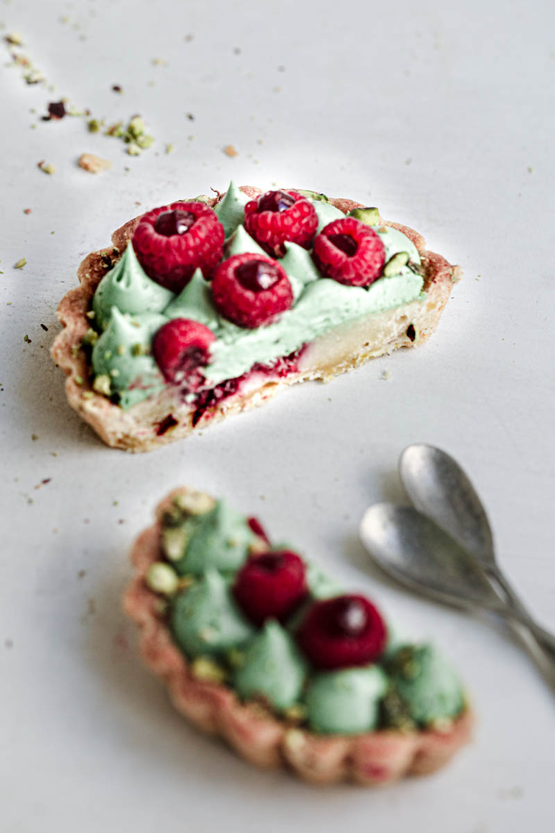 A 45° shot of a sliced tartlet with a spoon on the side.