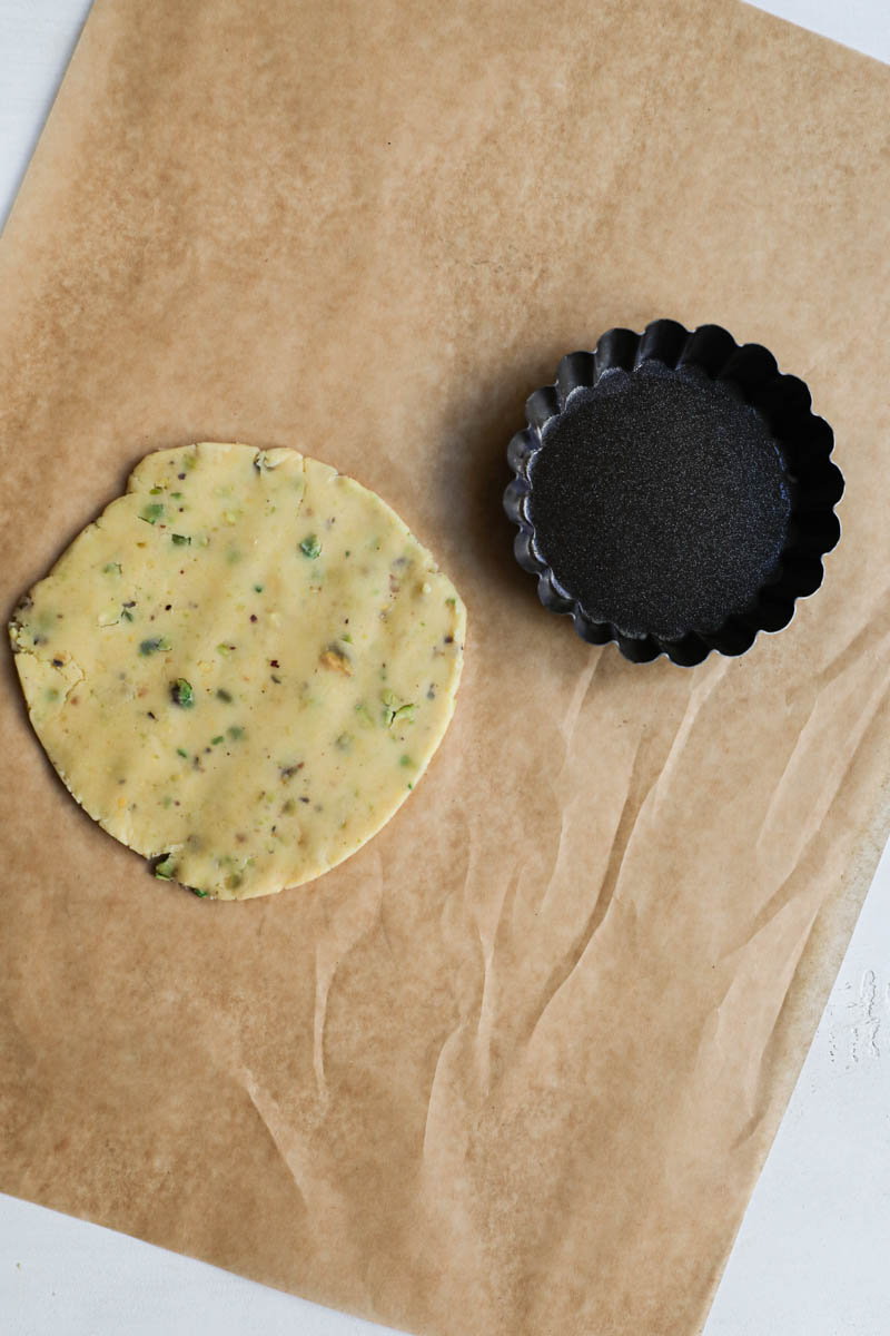 One piece of rolled crust cut in a small disk and the tartlet tin on the side.