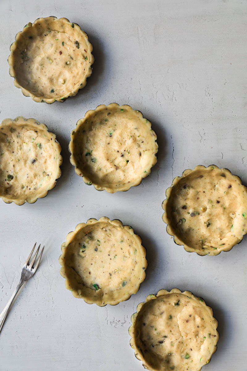 The tartlet tins lined with the pistachio shortbread crust.