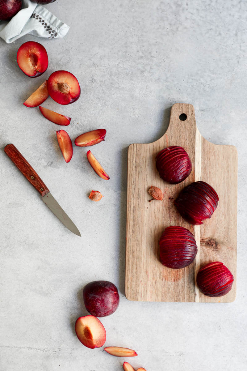 Overhead shot of sliced plums on a wooden chopping board