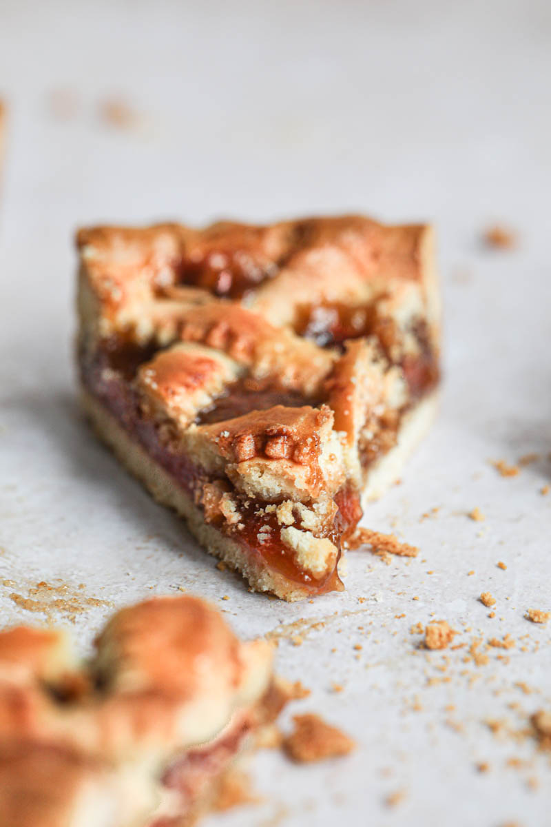 One slice of quince pie as seen from the front with a piece on the side.