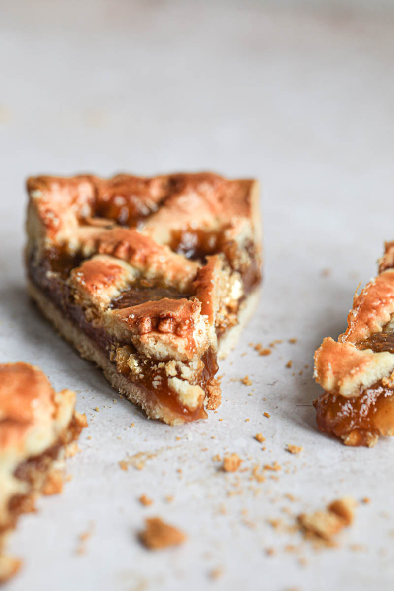 One slice of quince pie as seen from the front with a piece on the side.