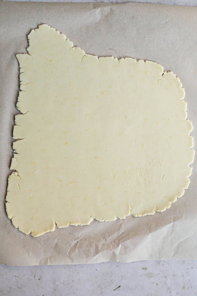 The rolled-out quince pie on top of a parchment paper.