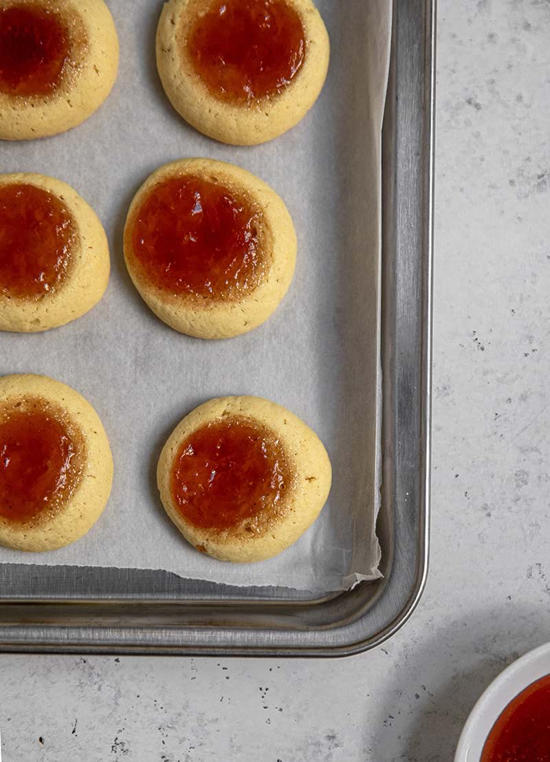 Thumbprint cookies just out the oven on a baking tray lined with parchment paper