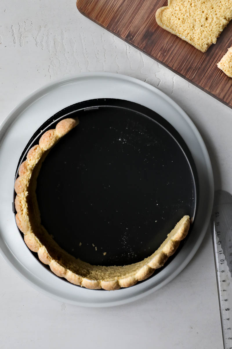 The cake ring with half of the trimmed ladyfinger band placed inside.