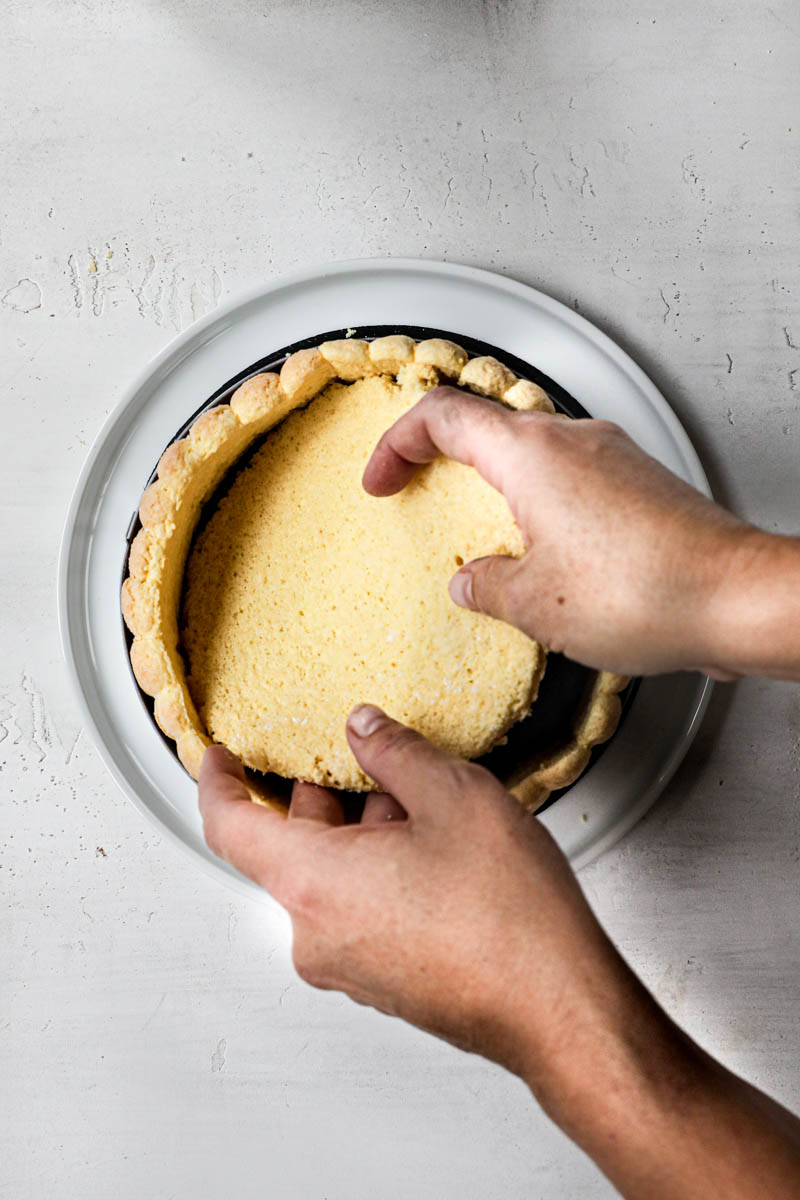 2 hands placing the ladyfinger cake disc inside the cake ring.