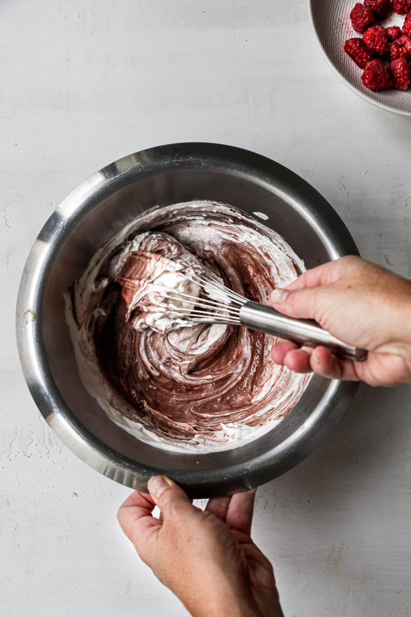 2 Hands mixing the cream and the chocolate ganache for the Bavarian cream.