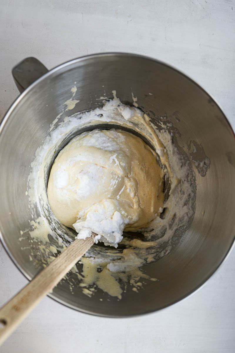 The egg whites and sugar/mixture mixed halfway for the ladyfinger cake inside a mixing bowl with a whisk.