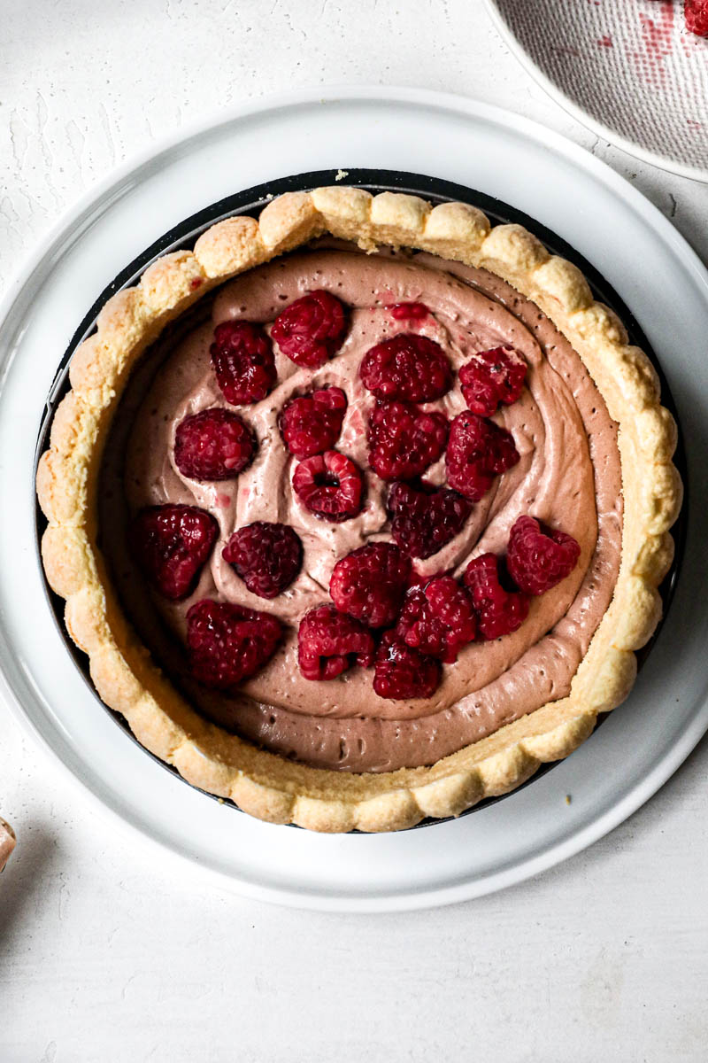 Raspberries placed into the chocolate Bavarian cream inside the charlotte cake.