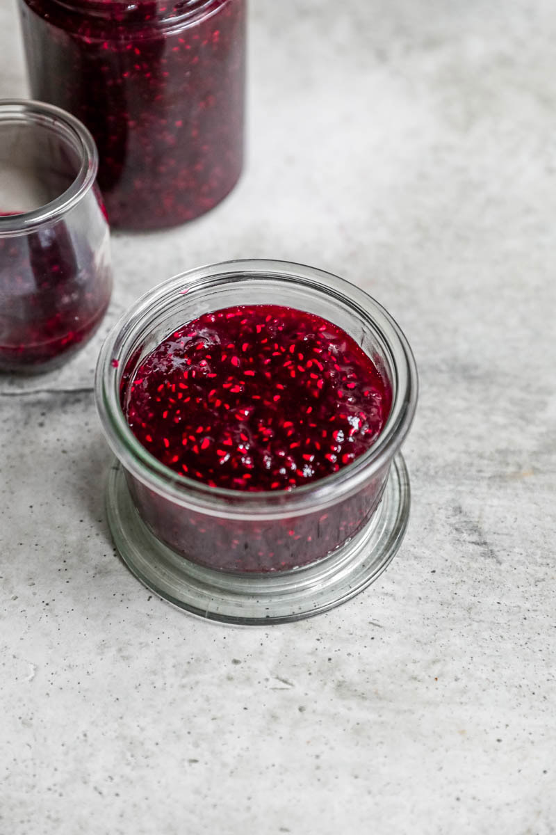 The raspberry jam inside a glass jar.