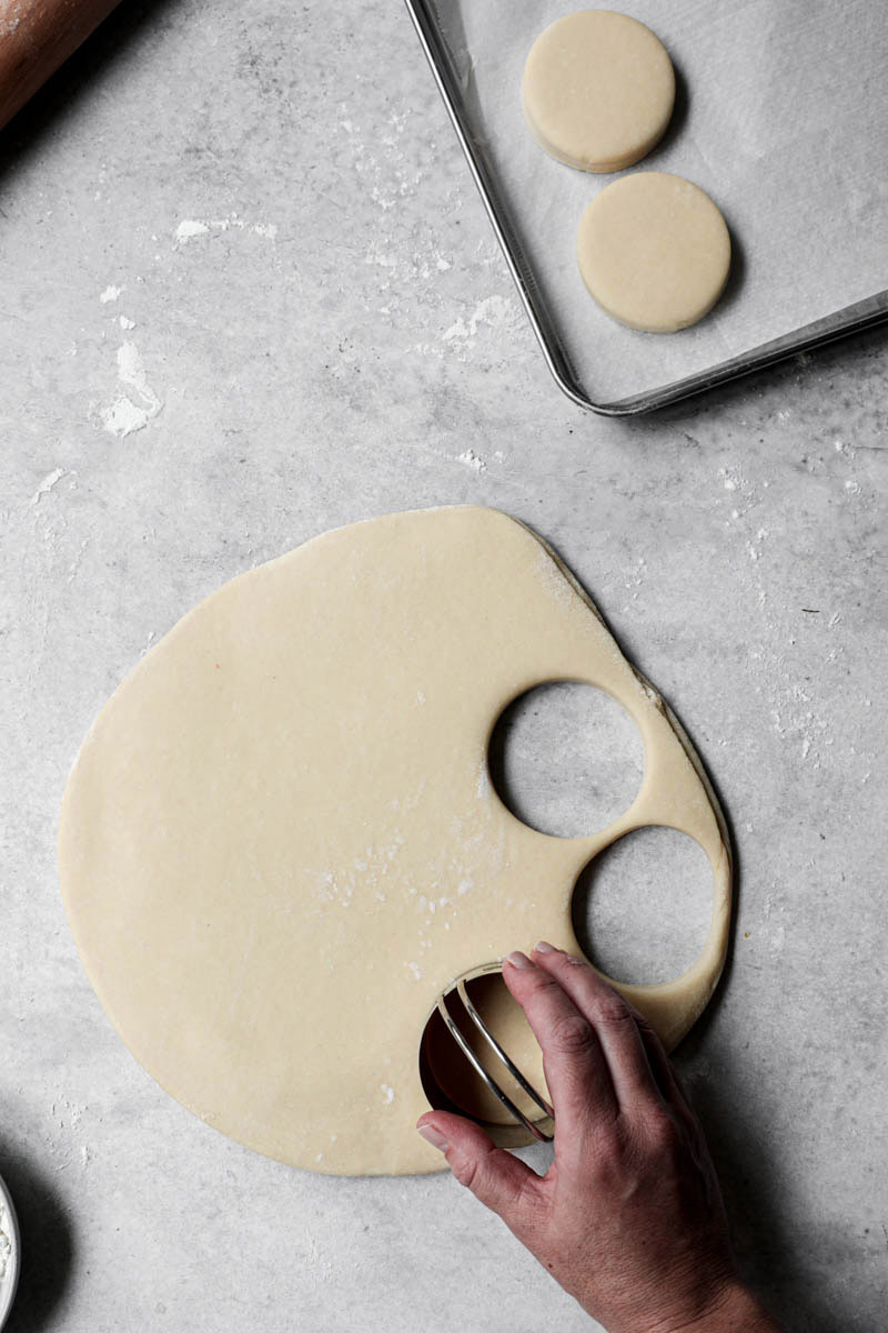 A hand cutting the donuts with a cutter.