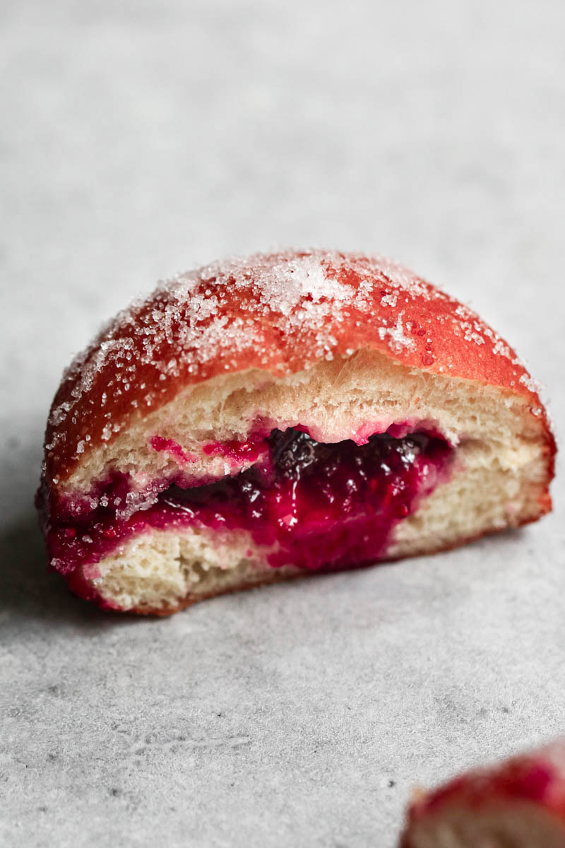 Closeup of a sliced filled raspberry jam brioche donut.