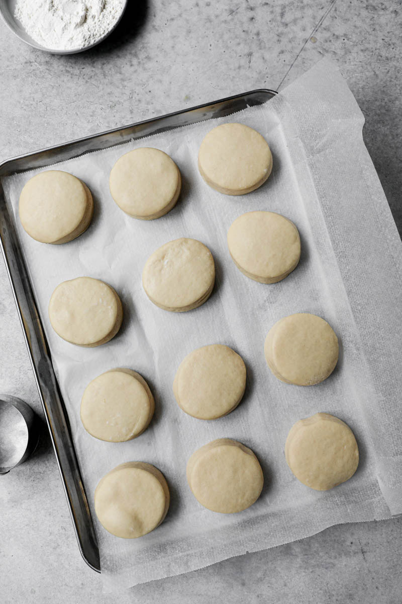 Raised donuts on a baking tray lined with parchment.