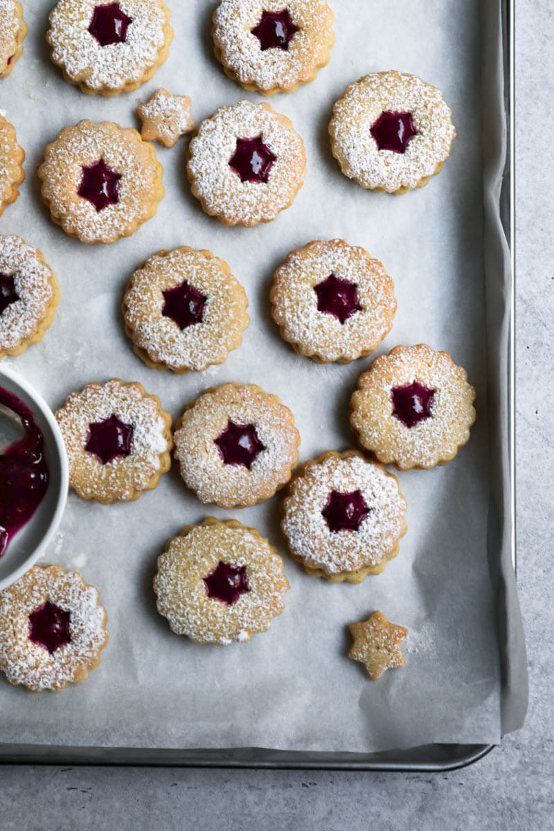 Raspberry linzer cookies on a baking tray lined with parchment paper