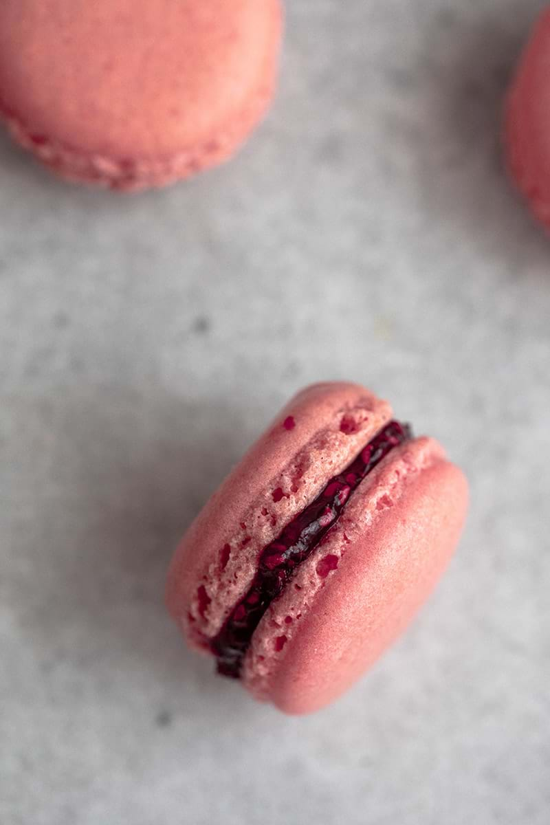 Overhead shot of one raspberry macaron filled with raspberry jam