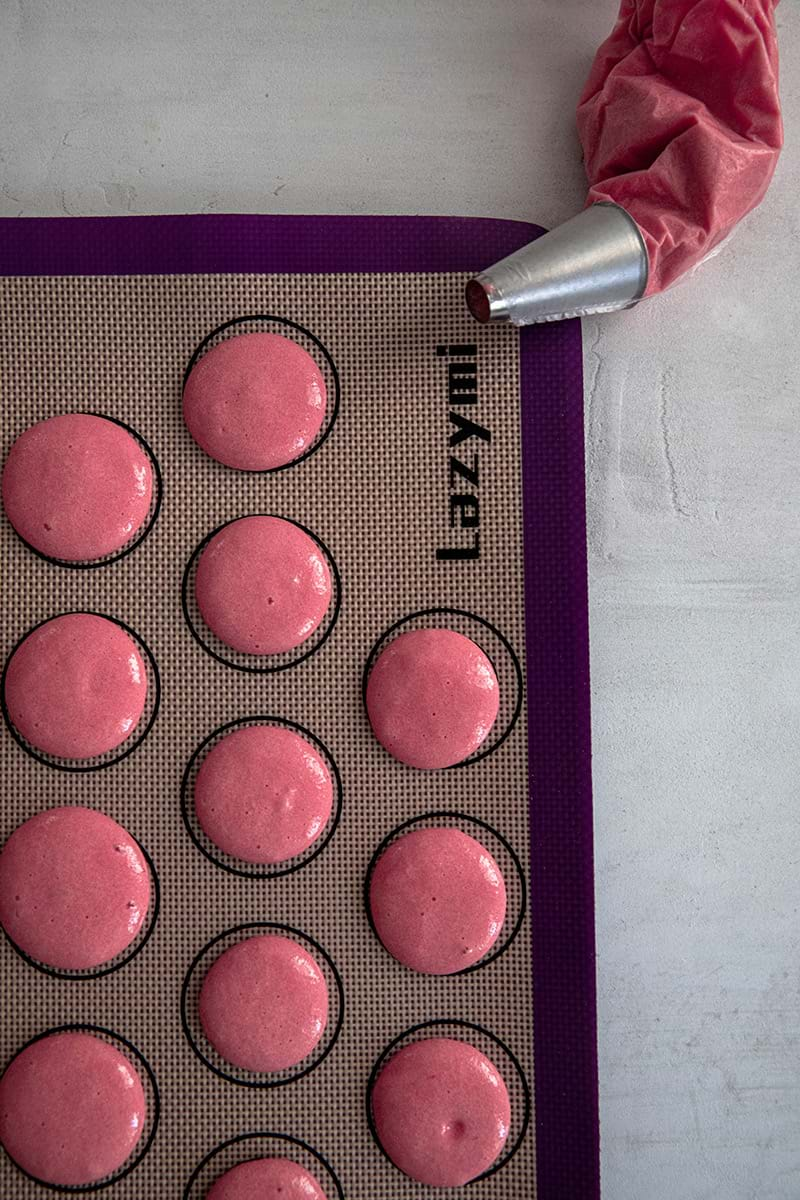 Raspberry macaron shells piped on silpad