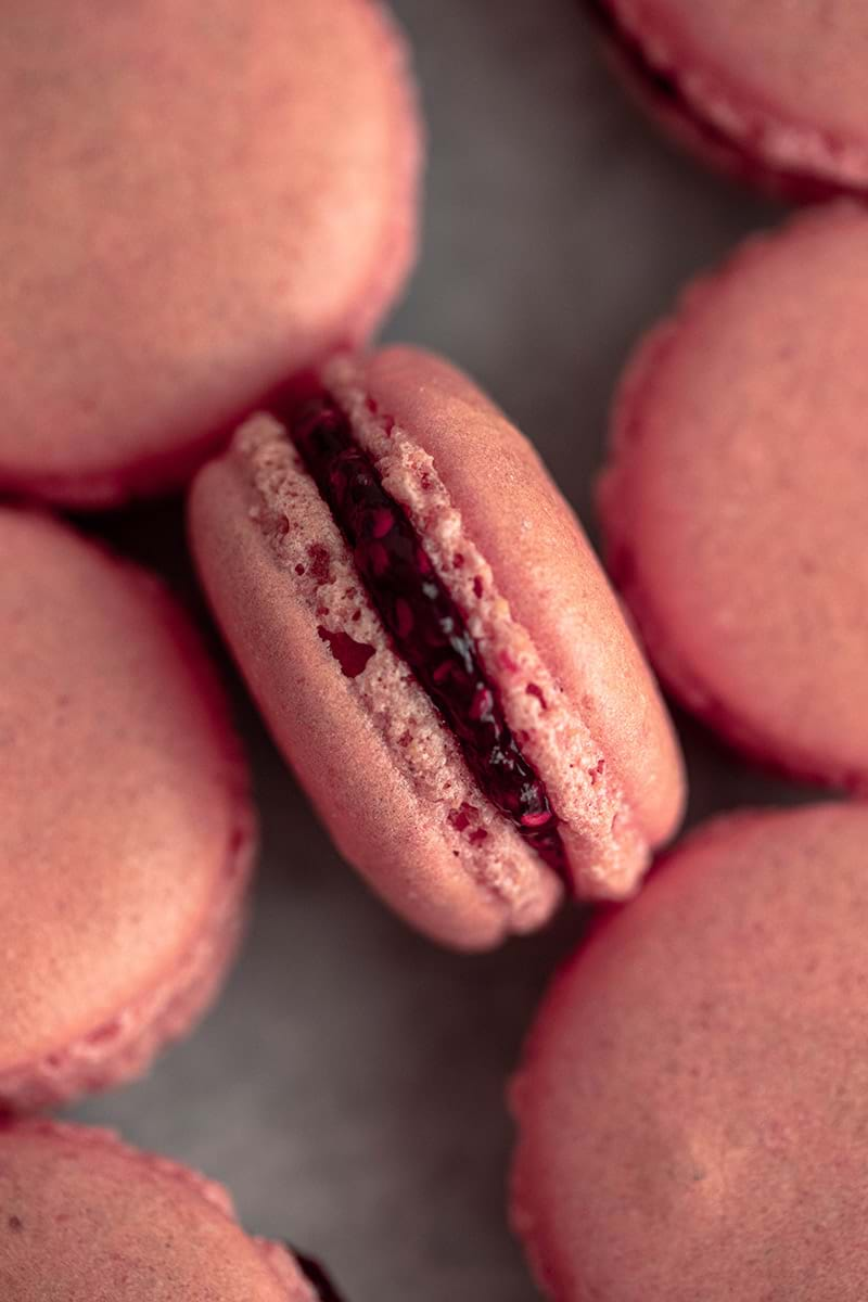 Overhead shot of one raspberry macaron filled with raspberry jam