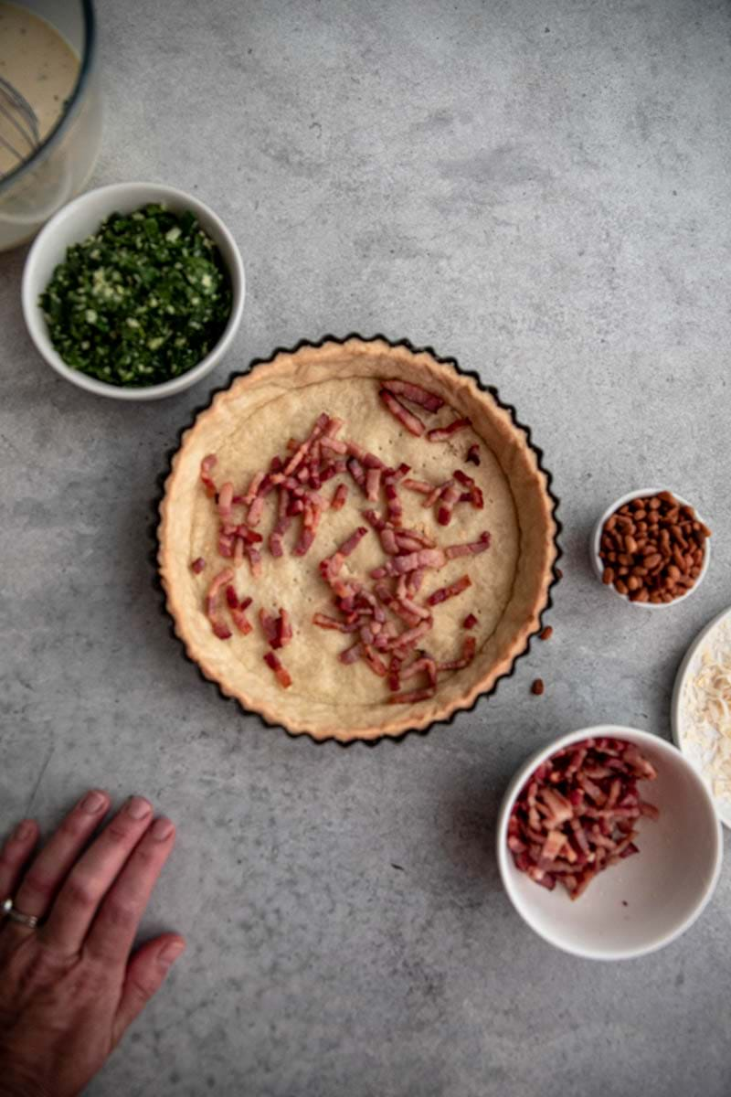 Cover the blind baked quiche crust with half the bacon