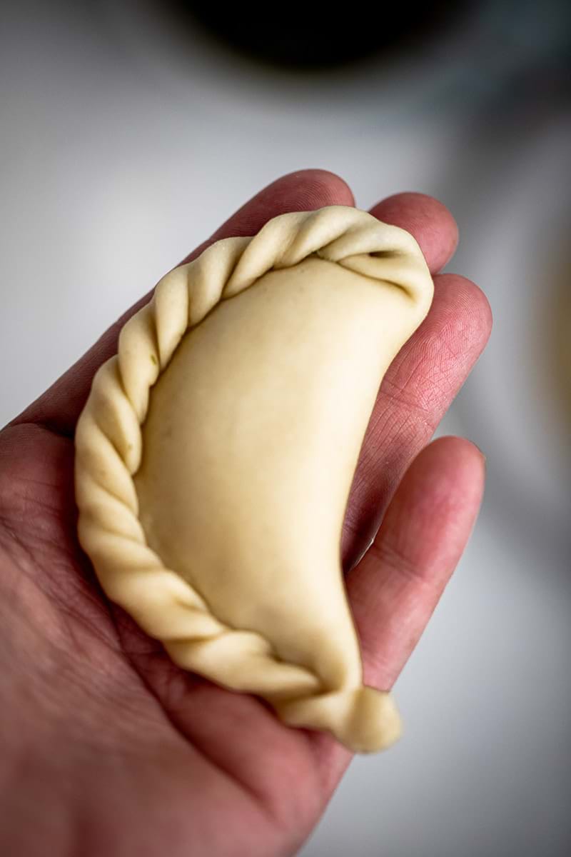 Closeup shot of one raw empanada on the palm of a hand