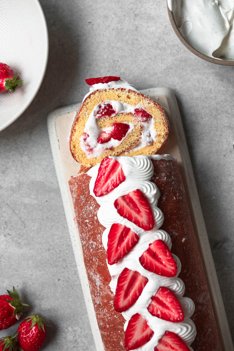 Closeup of the strawberry roll cake with a slice cut off as seen from above.