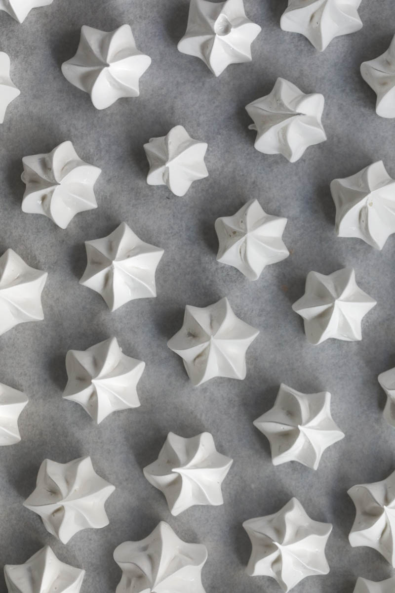 Close up of the pipped Swiss meringue kisses on a baking tray ready for the oven as seen from above.