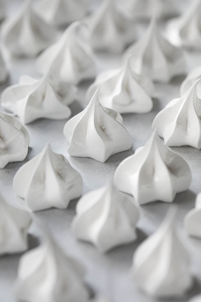 The pipped Swiss meringue kisses on a baking tray ready for the oven.