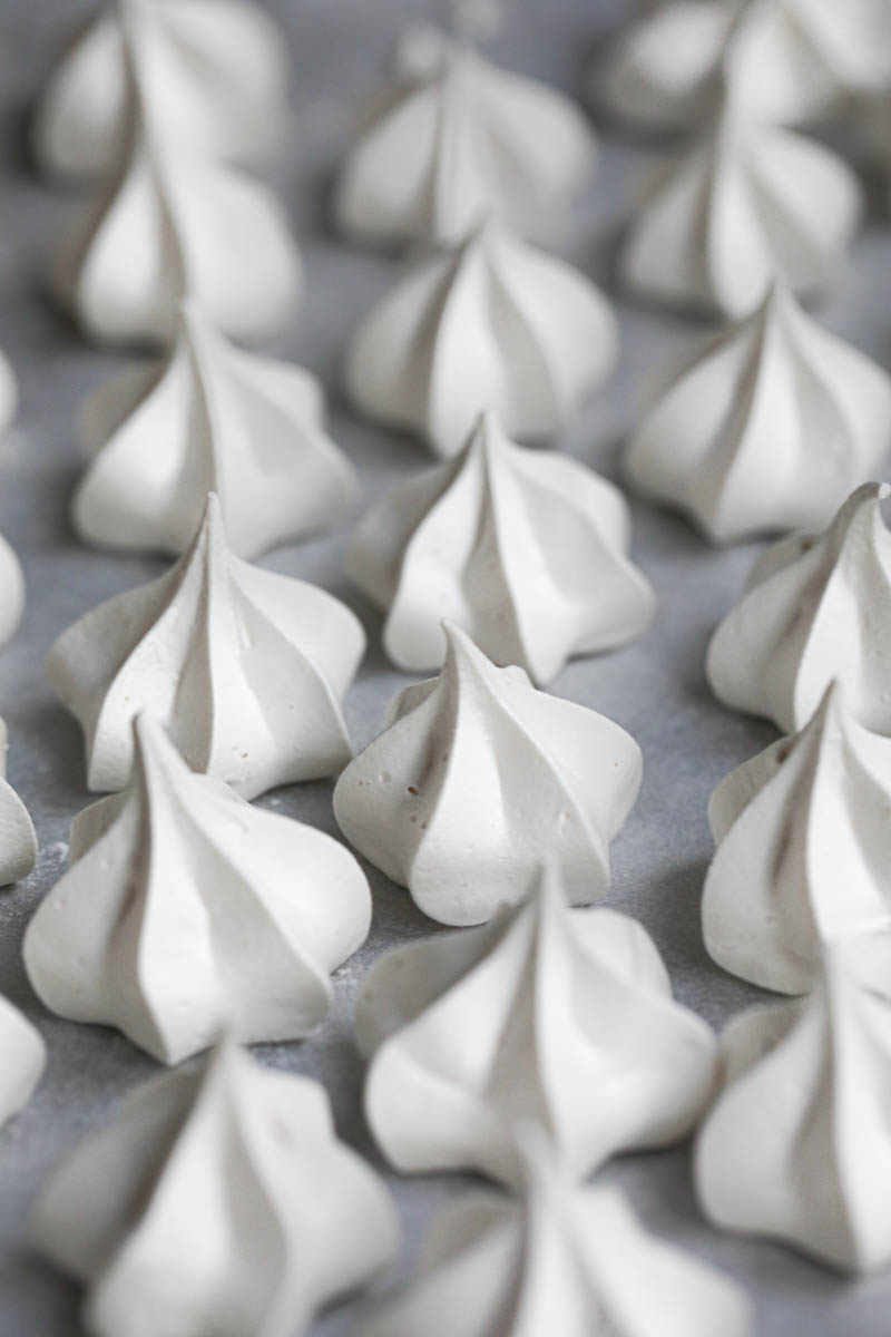 The baked Swiss meringue cookies on the baking tray lined with parchment paper.