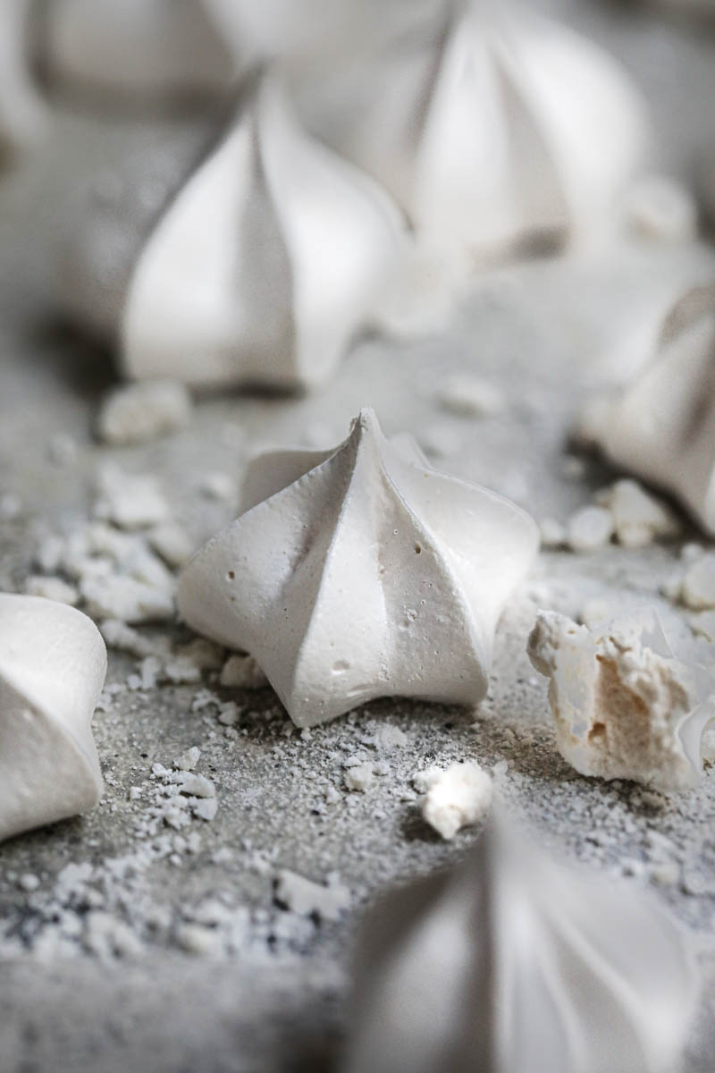 Close up of one meringue cookie with others blurry in the back of the frame.