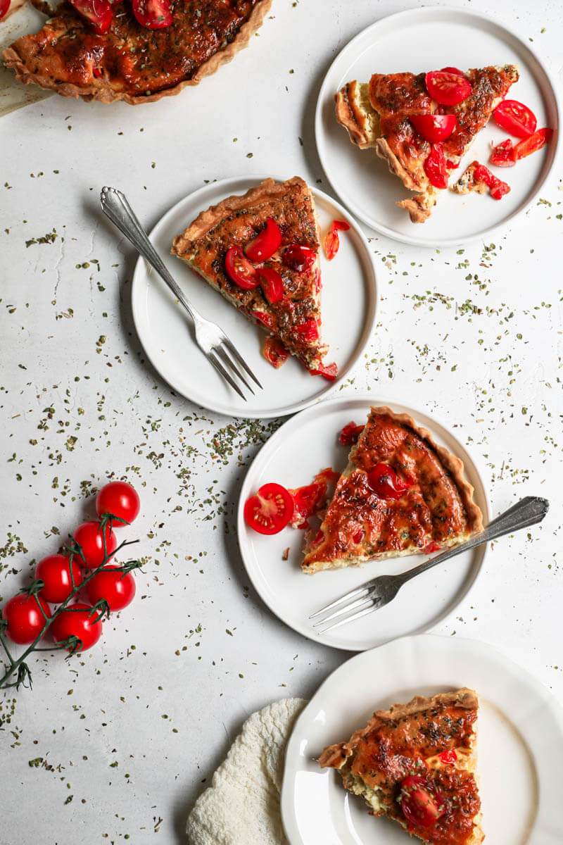 Overhead shot of four plates with one slice of quiche each