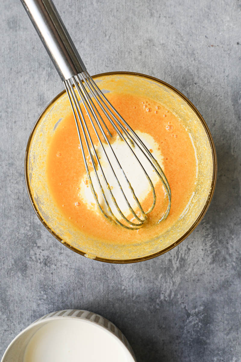 In the process of making vanilla bean crème brûlée: mixing the sugar, the egg yolks and the cold cream with a whisk using a small glass bowl.