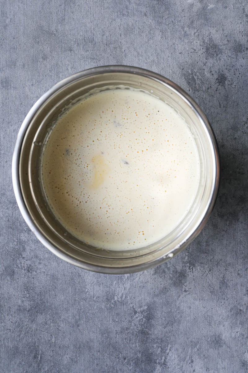 In the process of making vanilla bean crème brûlée: the vanilla crème brulee batter ready inside an inox bowl.