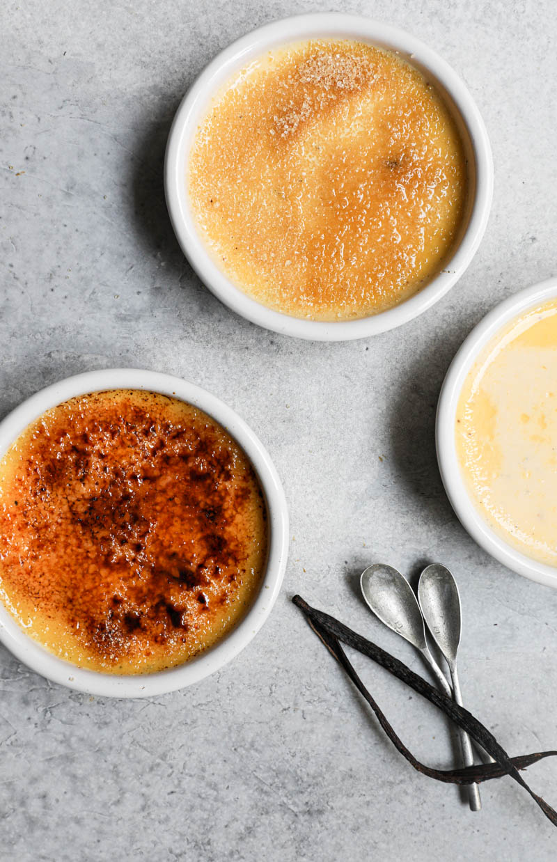 3 ramekins: one with the baked and chilled vanilla bean cream brulee, one with the crème brulee is sprinkled with brown sugar and one with the caramelized crème brulee.