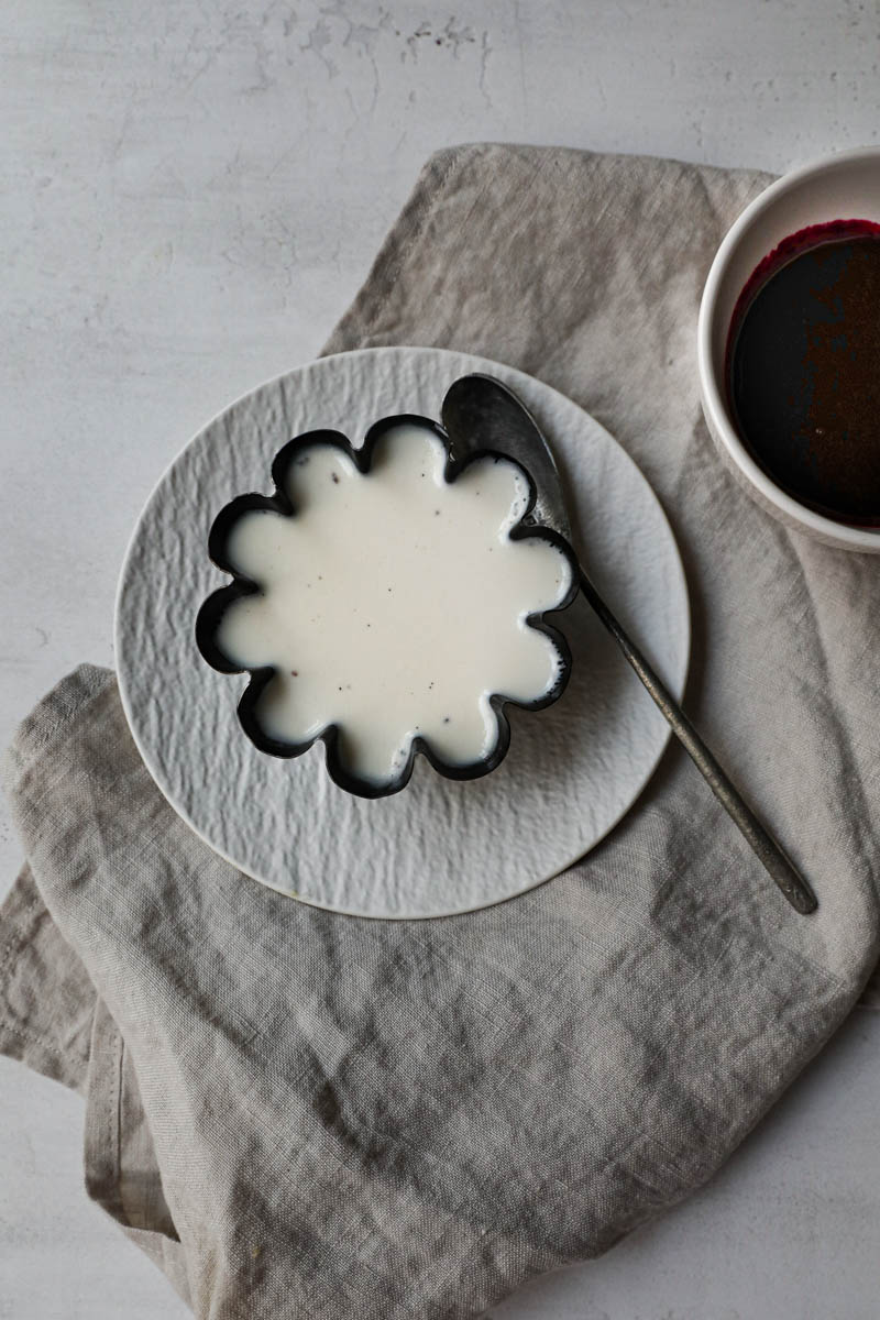 Panna cotta chilled and ready inside the mould placed on white plate on top of a beige linen cloth.