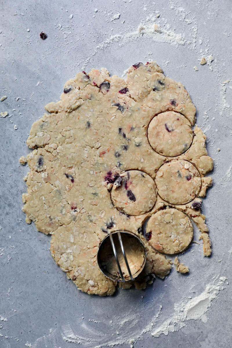 The rolled-out oatmeal cookie dough with a cookie cutter on it and some cookies are already cut out