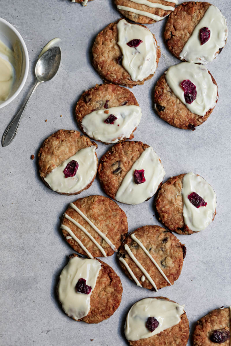 Baked cookies drizzled with white chocolate with a small bowl with white chocolate on the side