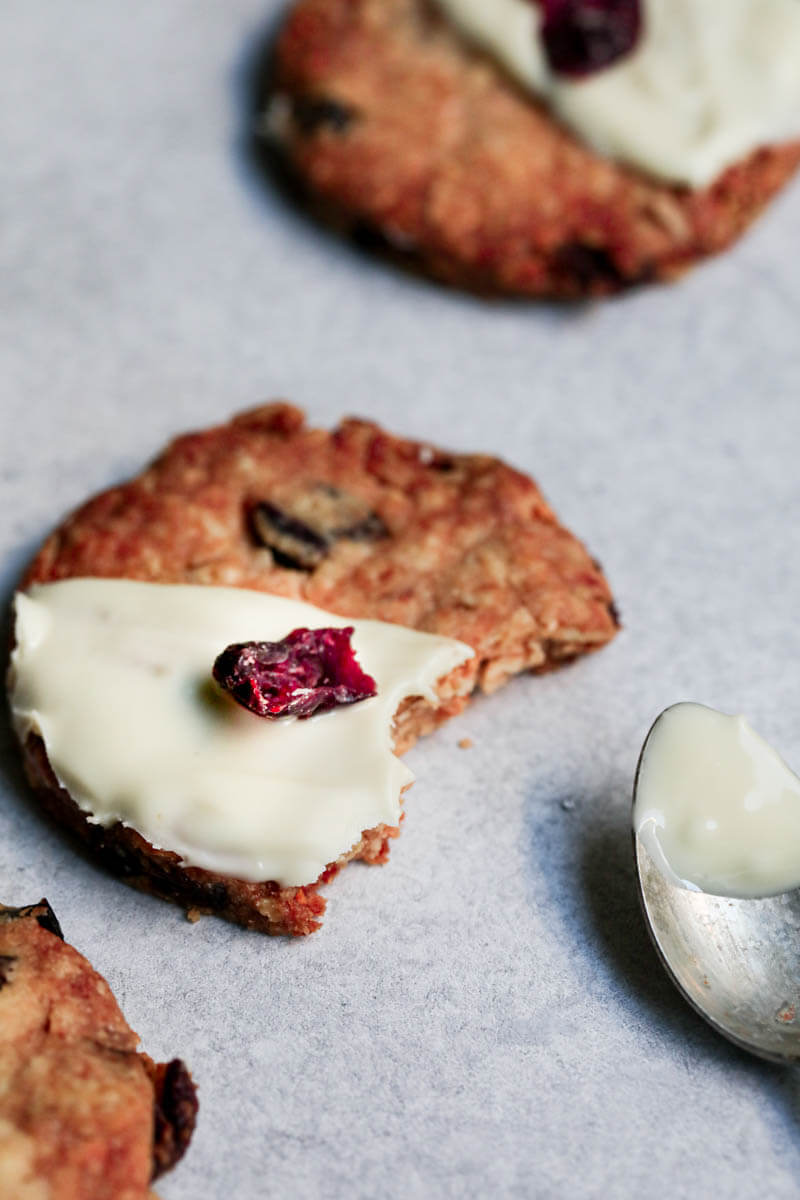 One oatmeal cookie minus a bite with a spoon on the side